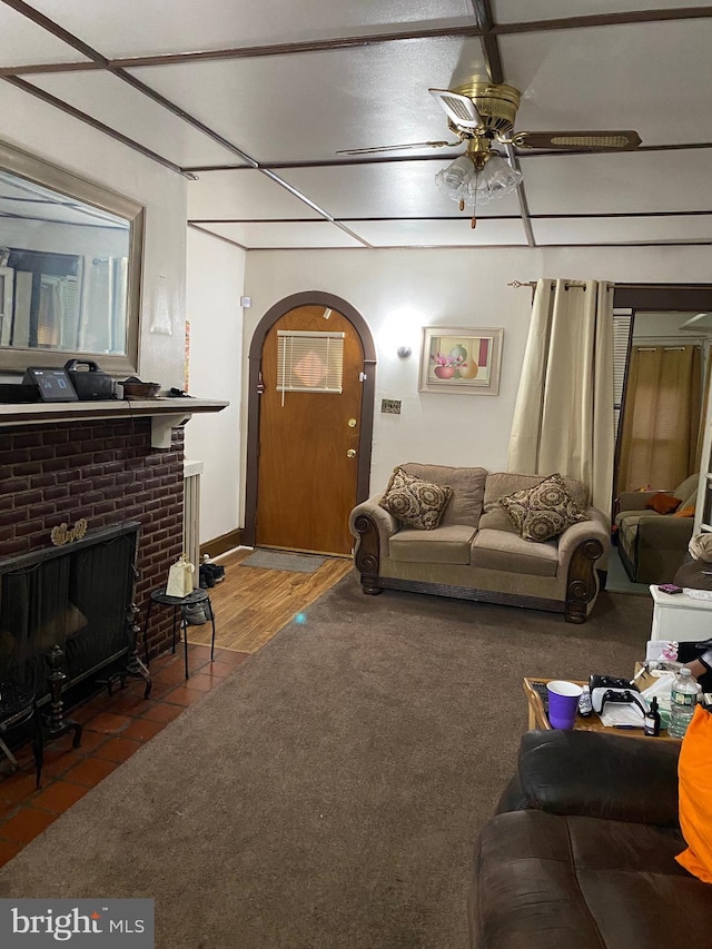 living room with hardwood / wood-style flooring, ceiling fan, and a brick fireplace