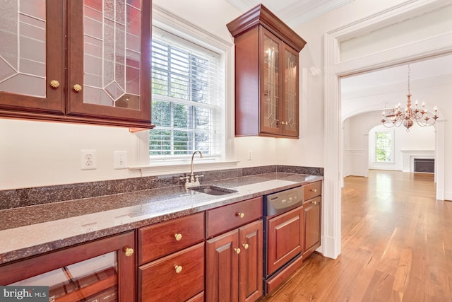 kitchen featuring light wood-type flooring, dark stone counters, crown molding, sink, and dishwasher