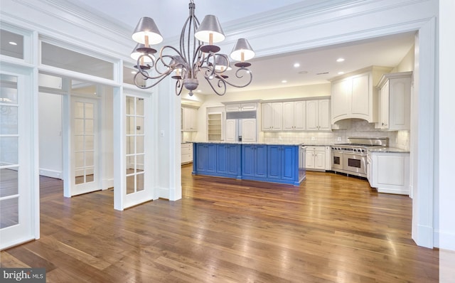 kitchen with dark hardwood / wood-style flooring, backsplash, high end appliances, a center island with sink, and a chandelier