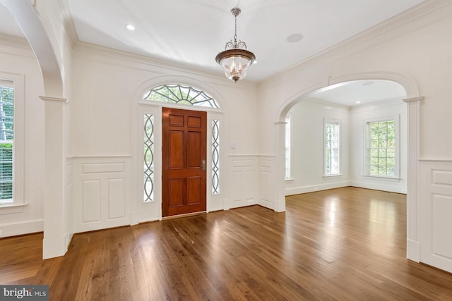 entrance foyer with ornamental molding, dark hardwood / wood-style flooring, and a healthy amount of sunlight