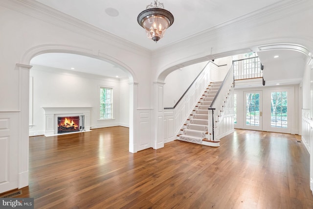 unfurnished living room with hardwood / wood-style floors, ornate columns, and ornamental molding