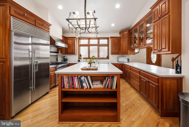 kitchen with a chandelier, light hardwood / wood-style flooring, a center island, high quality appliances, and lofted ceiling