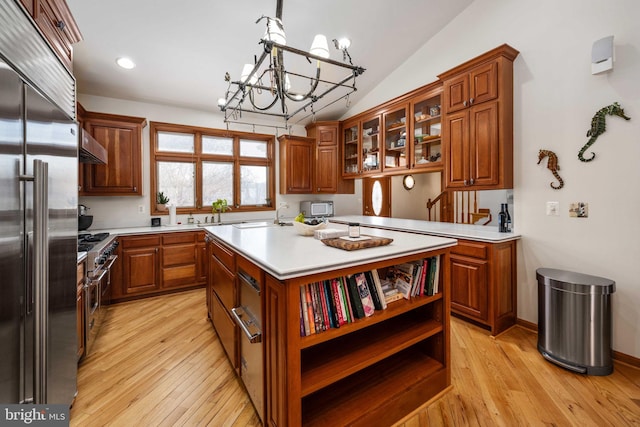 kitchen with a notable chandelier, light hardwood / wood-style floors, wall chimney exhaust hood, and premium appliances