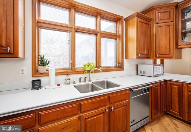 kitchen with sink, dishwashing machine, and light hardwood / wood-style flooring