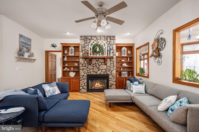 living room with a fireplace, ceiling fan, and light hardwood / wood-style flooring