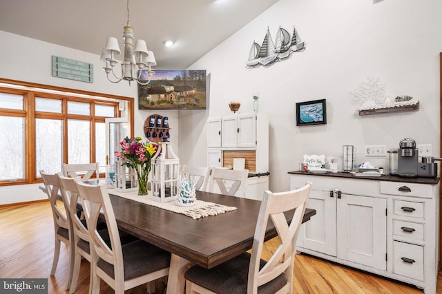 dining area featuring a notable chandelier, light hardwood / wood-style flooring, and vaulted ceiling