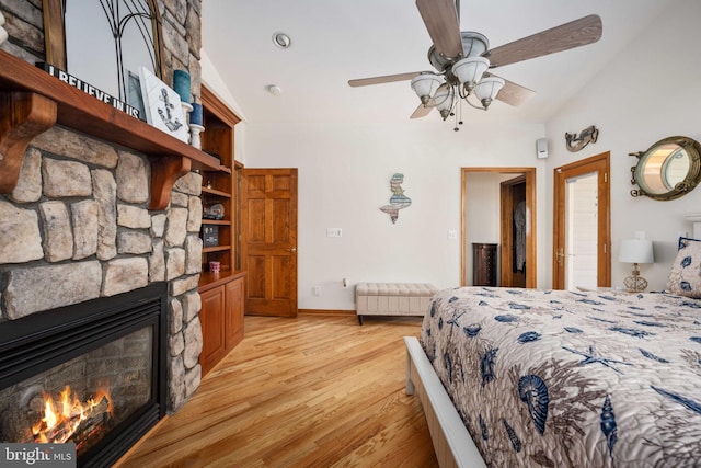 bedroom featuring ceiling fan, light hardwood / wood-style flooring, a fireplace, and lofted ceiling