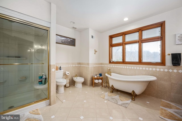 bathroom with tile walls, a bidet, independent shower and bath, and toilet