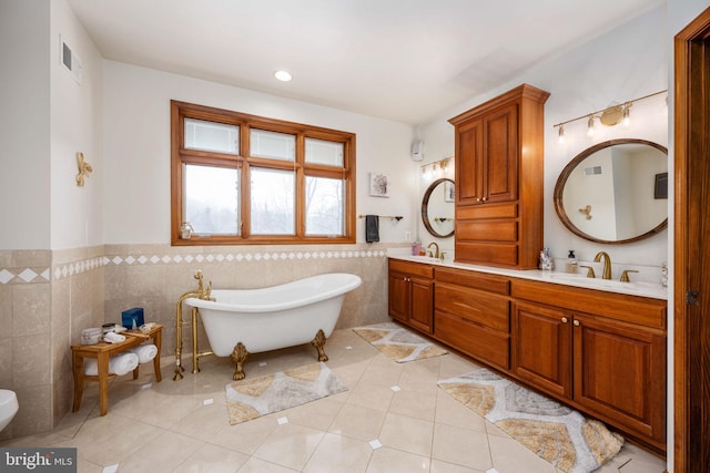 bathroom with dual bowl vanity, a washtub, tile walls, and tile floors