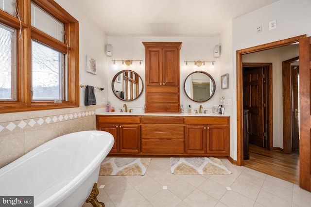 bathroom with a tub, double vanity, tile flooring, and tile walls