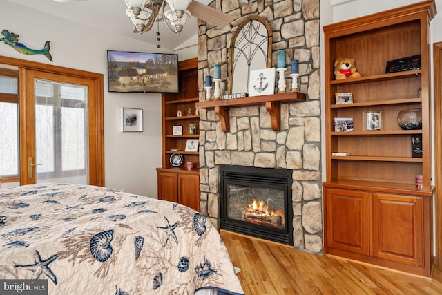 bedroom with a stone fireplace and light hardwood / wood-style flooring