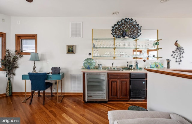 bar featuring hardwood / wood-style floors, sink, and beverage cooler