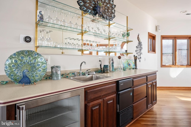 kitchen featuring dark brown cabinets, sink, and light hardwood / wood-style flooring