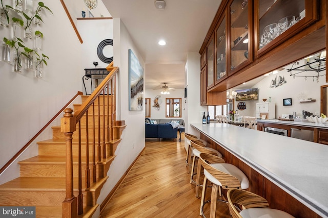 kitchen with light hardwood / wood-style floors, a kitchen breakfast bar, and ceiling fan