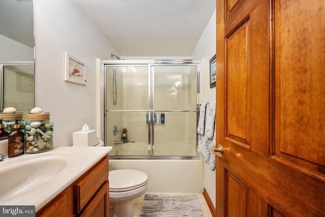 full bathroom featuring tile flooring, bath / shower combo with glass door, vanity, and toilet