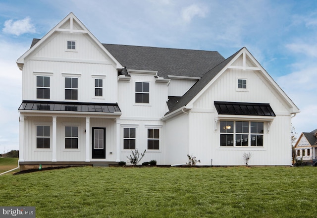 modern farmhouse featuring board and batten siding, a front yard, and a standing seam roof