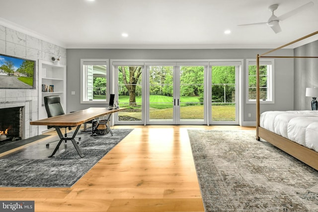 bedroom with hardwood / wood-style floors, a tile fireplace, crown molding, and multiple windows