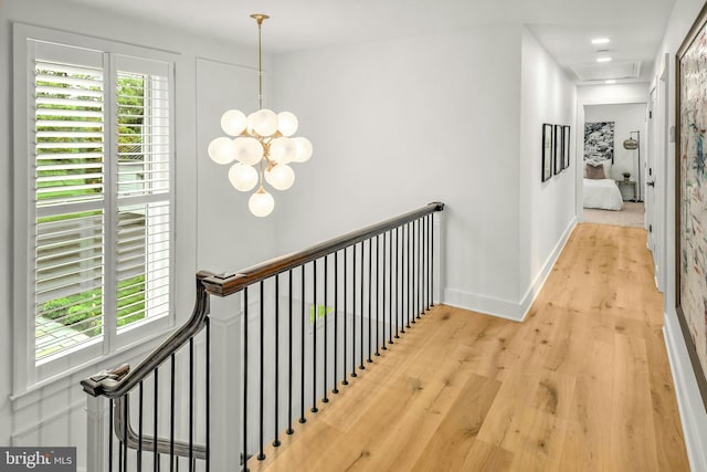 corridor featuring plenty of natural light, light hardwood / wood-style flooring, and a notable chandelier