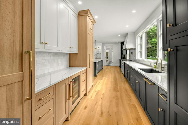 kitchen featuring light stone countertops, light hardwood / wood-style flooring, sink, tasteful backsplash, and light brown cabinetry