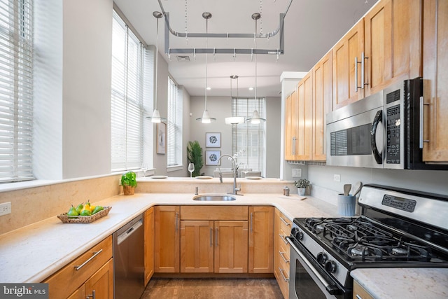 kitchen featuring hanging light fixtures, appliances with stainless steel finishes, a wealth of natural light, and sink