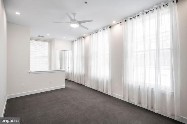 unfurnished room with ceiling fan and dark colored carpet