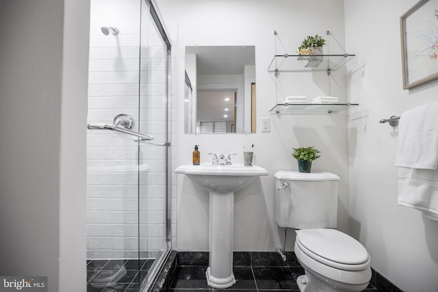 bathroom with tile patterned floors, sink, tiled shower, and toilet