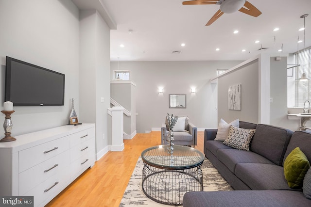 living room featuring ceiling fan, sink, and light hardwood / wood-style floors