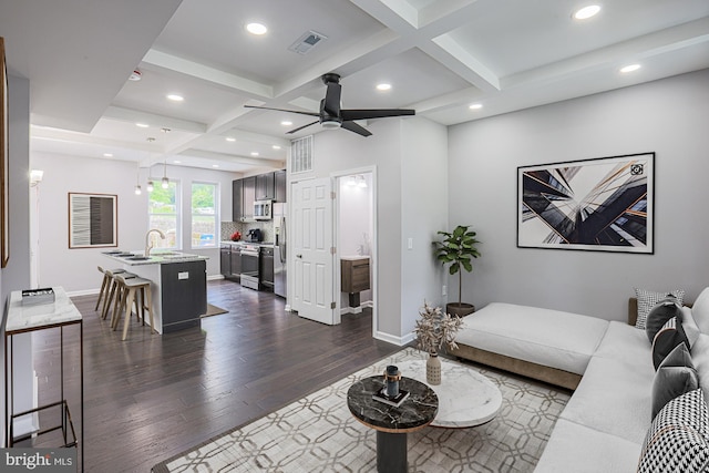 living room with beam ceiling, dark hardwood / wood-style floors, coffered ceiling, and sink