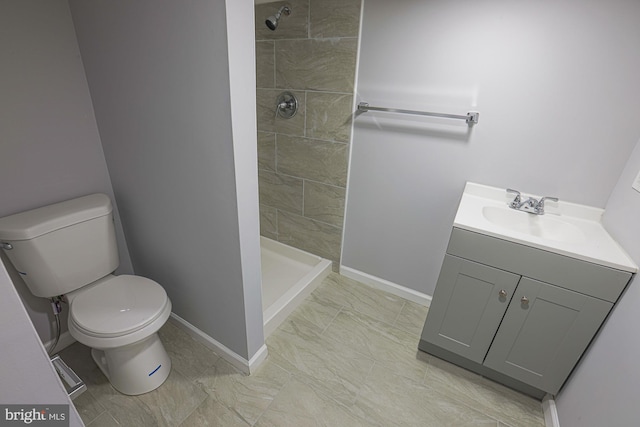 bathroom with tiled shower, vanity, and toilet