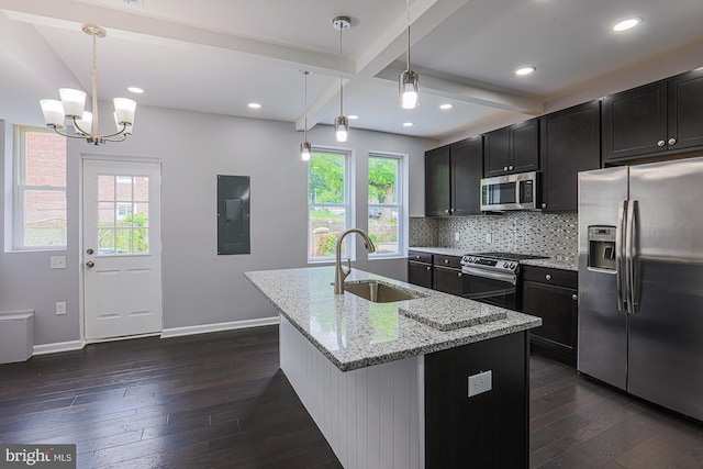 kitchen with sink, an island with sink, appliances with stainless steel finishes, decorative light fixtures, and beam ceiling