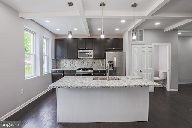 kitchen featuring stainless steel appliances, sink, dark hardwood / wood-style floors, hanging light fixtures, and an island with sink