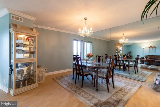 dining area featuring wood-type flooring, ornamental molding, and an inviting chandelier