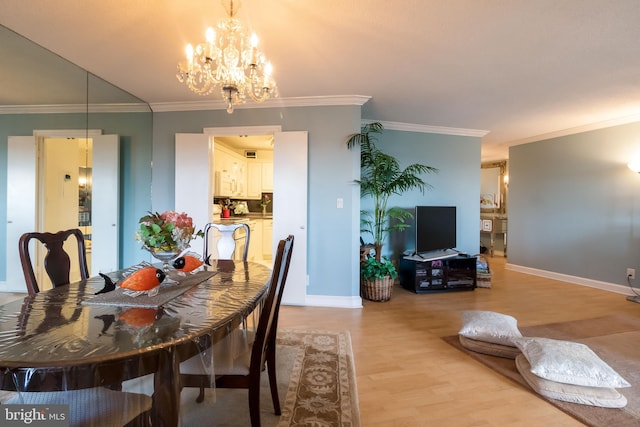 dining space with light hardwood / wood-style floors, ornamental molding, and a notable chandelier