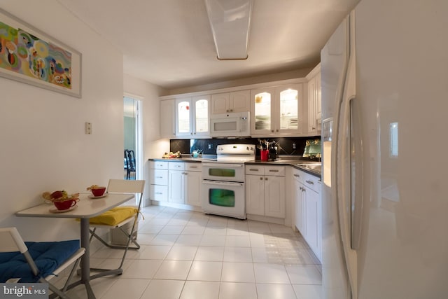 kitchen featuring white cabinets, light tile flooring, white appliances, and backsplash