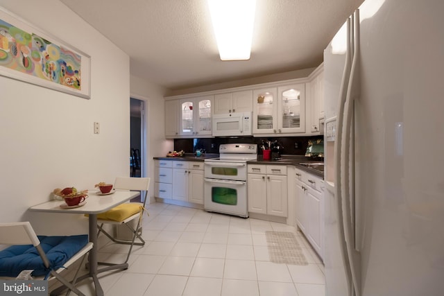 kitchen with backsplash, white cabinets, white appliances, and light tile flooring