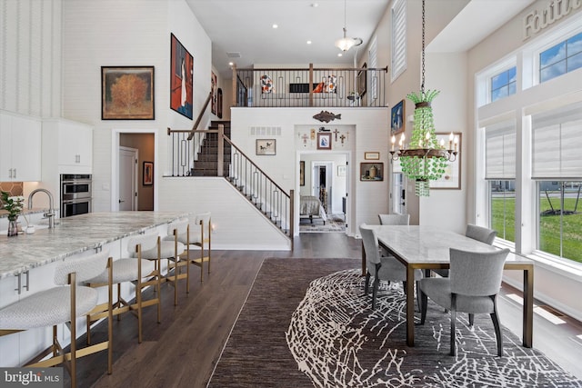 dining area featuring dark hardwood / wood-style flooring, plenty of natural light, and a high ceiling