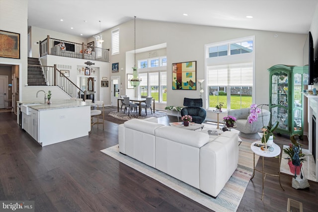 living room featuring high vaulted ceiling, sink, and dark hardwood / wood-style floors