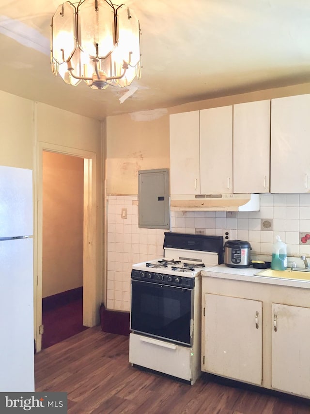 kitchen featuring white appliances, electric panel, sink, dark hardwood / wood-style floors, and decorative backsplash