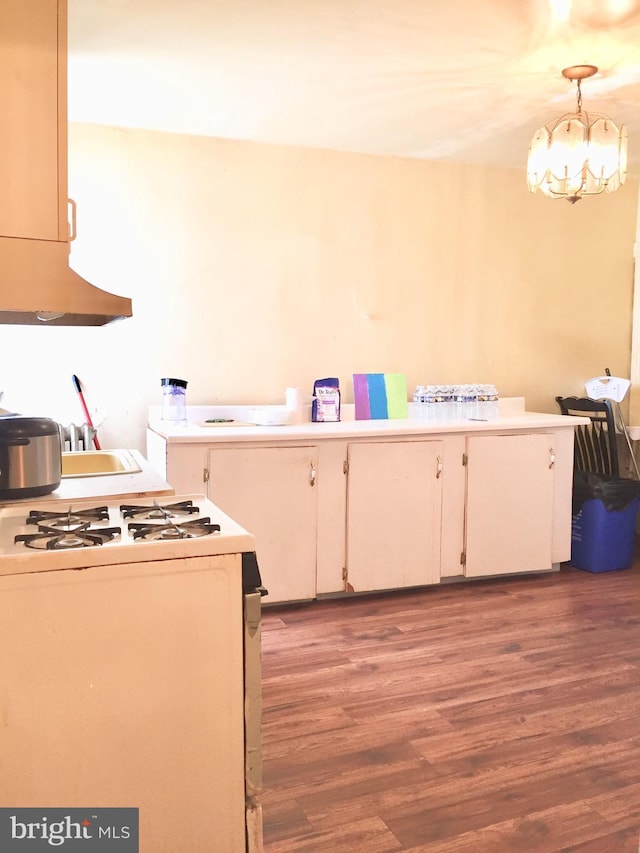 kitchen featuring pendant lighting, sink, gas range gas stove, wood-type flooring, and a chandelier