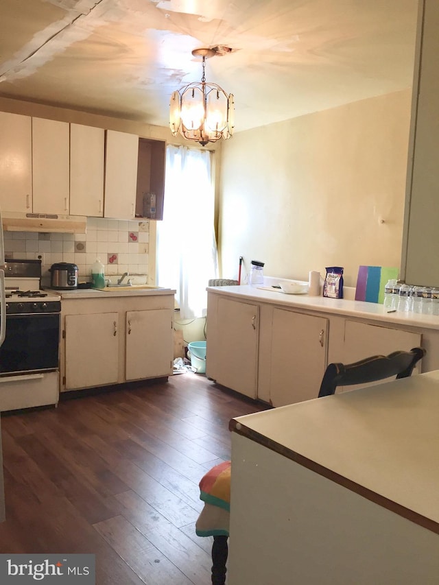 kitchen with white stove, a notable chandelier, white cabinetry, and hanging light fixtures