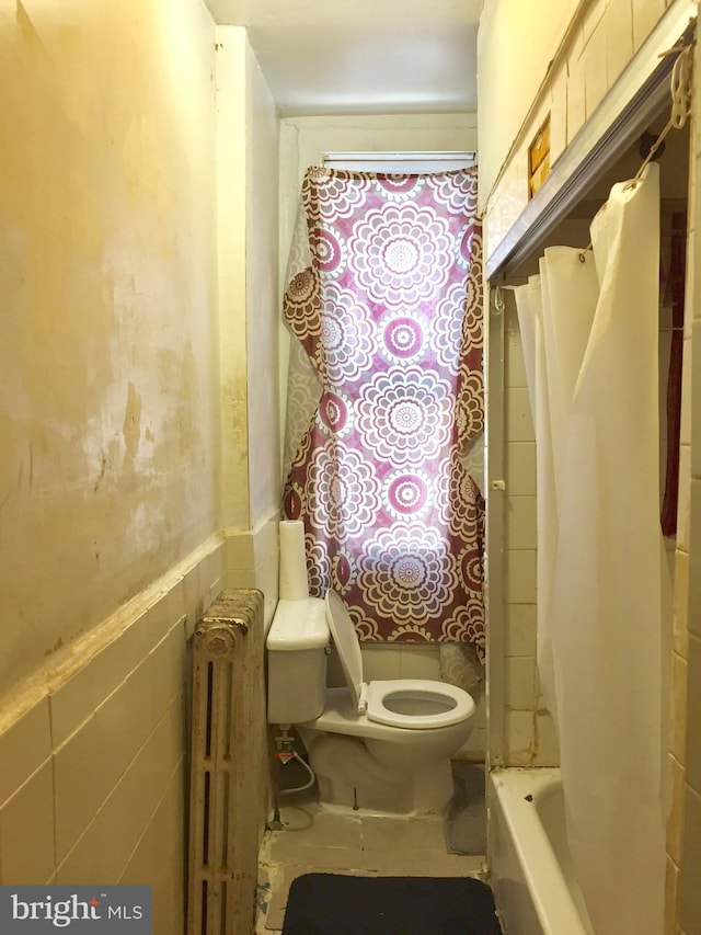 bathroom with radiator heating unit, shower / tub combo, toilet, and tile walls