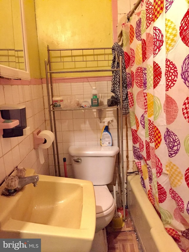 full bathroom with parquet floors, shower / bath combination with curtain, sink, toilet, and tile walls