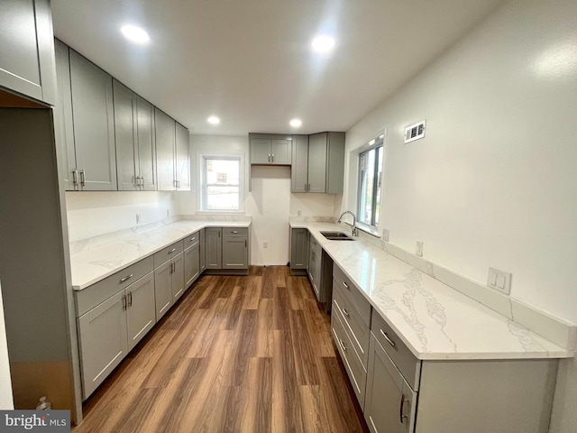 kitchen with gray cabinetry, dark hardwood / wood-style floors, light stone counters, and sink