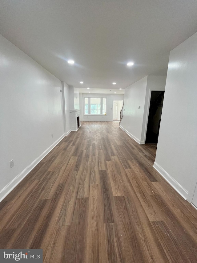 unfurnished living room with dark hardwood / wood-style flooring and a brick fireplace