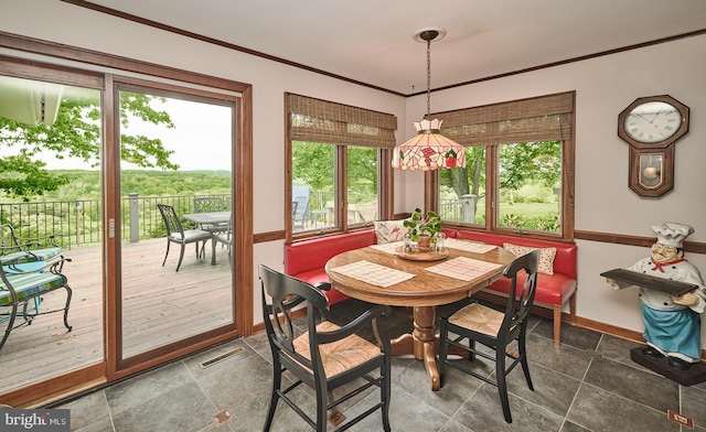 dining room featuring a wealth of natural light, ornamental molding, and dark tile floors