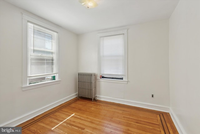 empty room featuring radiator and hardwood / wood-style floors