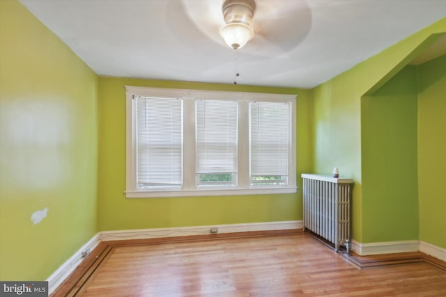 spare room featuring ceiling fan, light hardwood / wood-style flooring, and radiator heating unit