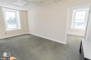 carpeted empty room with a drop ceiling