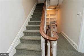 stairway featuring dark carpet