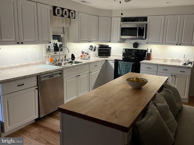 kitchen featuring wooden counters, white cabinets, sink, light hardwood / wood-style flooring, and stainless steel appliances